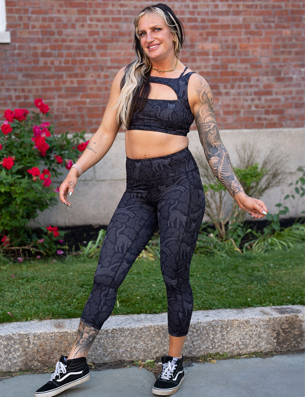 model wearing the capri black and grey bats and cats skeleton leggings and sports bra
