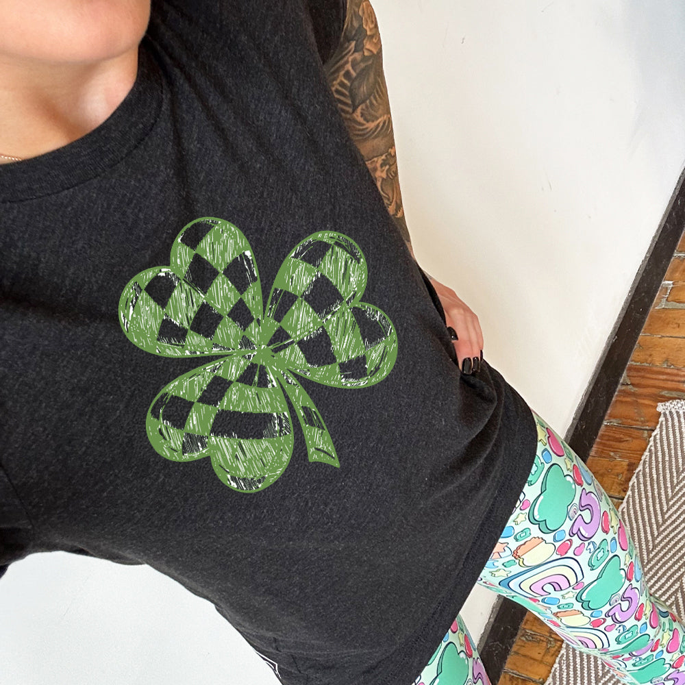 Person wearing a black t-shirt with a green shamrock design.