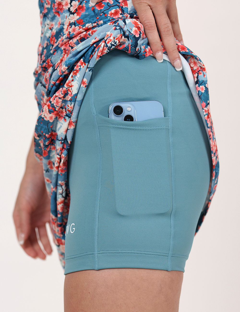 the cherry pattern dress lifted up to show a phone in the pockets of the shorts underneath