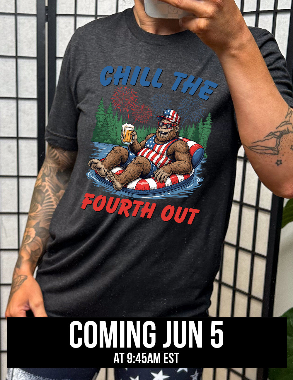 black unisex tee with the graphic of a grinning Bigfoot holding a beer, wearing sunglasses and an American flag outfit, in an American flag tube, in the water, with a background of trees, with fireworks above, and the words saying "chill the fourth out" on it, coming june 5th