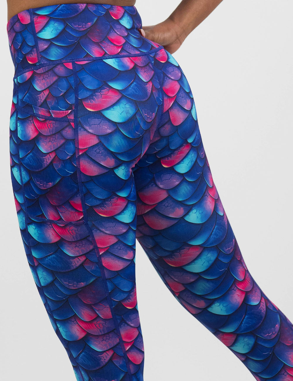 back of the blue, purple, and red colored dragon scale leggings against a white background