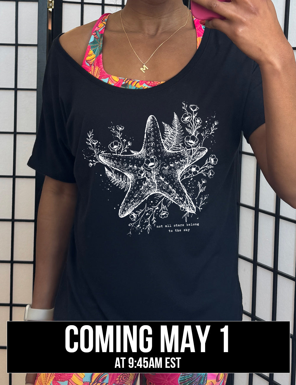 black slouchy tee with the graphic of a very detailed starfish among sea plants and flowers, with little bubbles, and the small words underneath it all that say "not all stars belong to the sky", coming soon