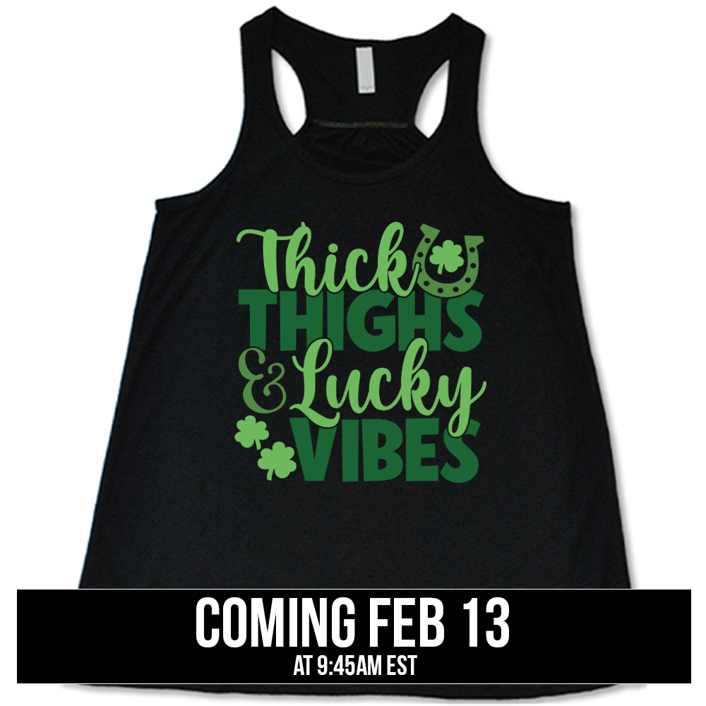 black flowy tank with the words "thick thighs & lucky vibes" on it, with graphics of a horseshoe and a few shamrocks, coming soon