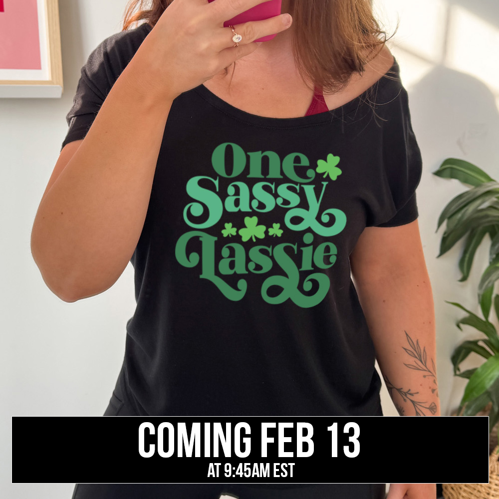 black slouchy tee with the words "one sassy lassy" on it, with a few shamrock graphics, coming soon