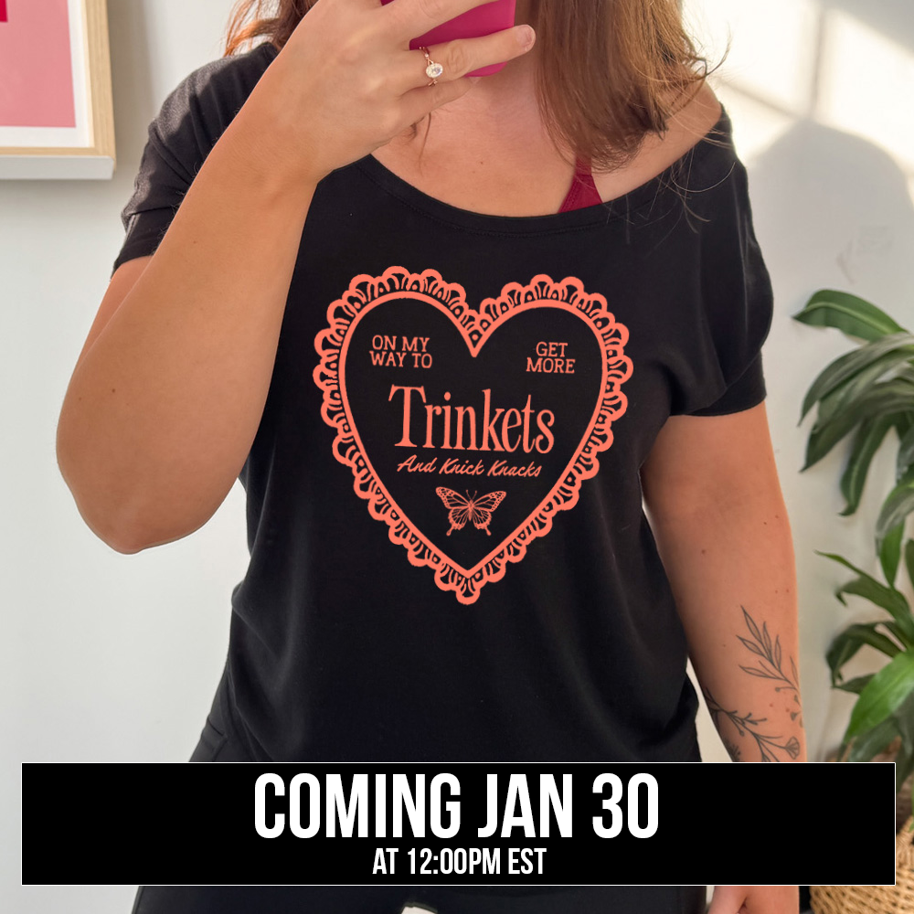 blacky slouchy tee with the graphic of a large heart with a lacy border, and within it the words "on my way to get more trinkets and Knick Knacks" and the graphic of a little butterfly, coming soon