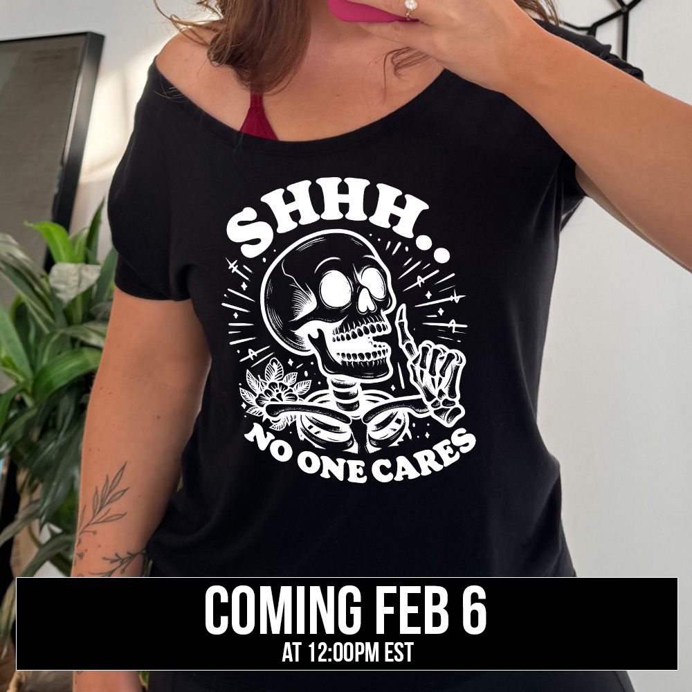 black slouchy tee with the words "Shhh.. no one cares" on it, with the graphic of a skeleton holding a finger to its lips, coming soon