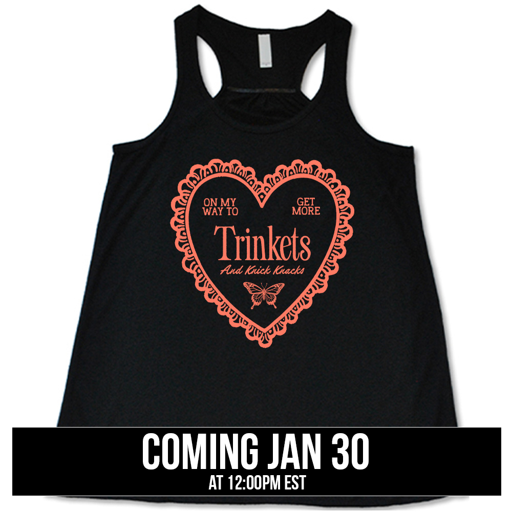 black flowy tank with the graphic of a large heart with a lacy border, and within it the words "on my way to get more trinkets and Knick Knacks" and the graphic of a little butterfly, coming soon