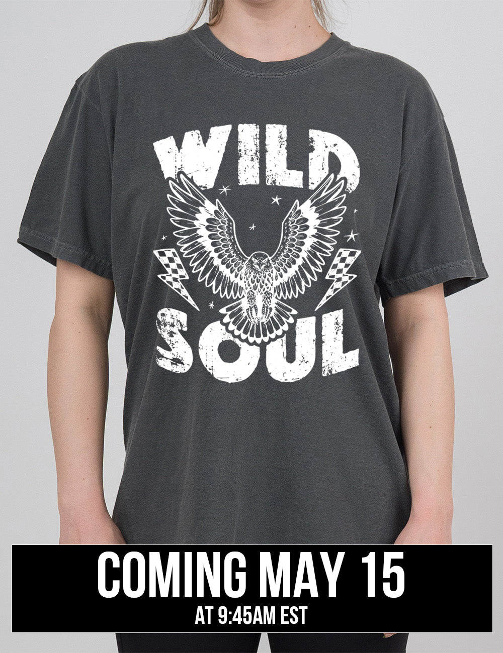 pepper modern tee with print placement on the front, with the words "wild soul" on it, with a large eagle graphic, with wings in flight, in the middle of the words, with a checkered lightning bolt on either side of it, with a few stars scattered around it, coming may 15th