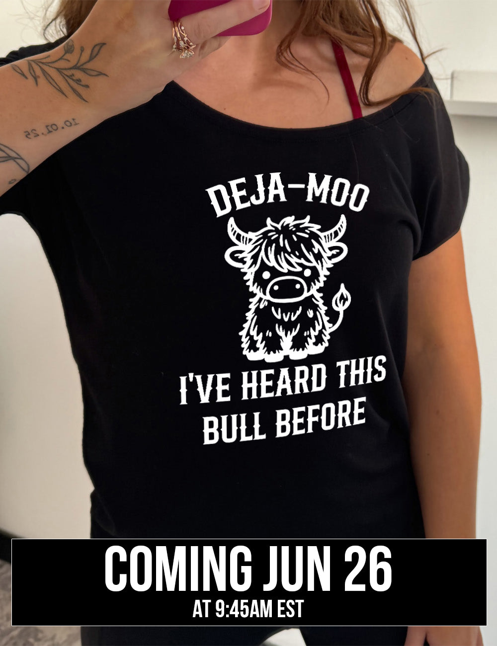 black slouchy tee with the words "deja-moo I've heard this bull before" on it, around the graphic of a bull, sitting facing forward, coming june 26th