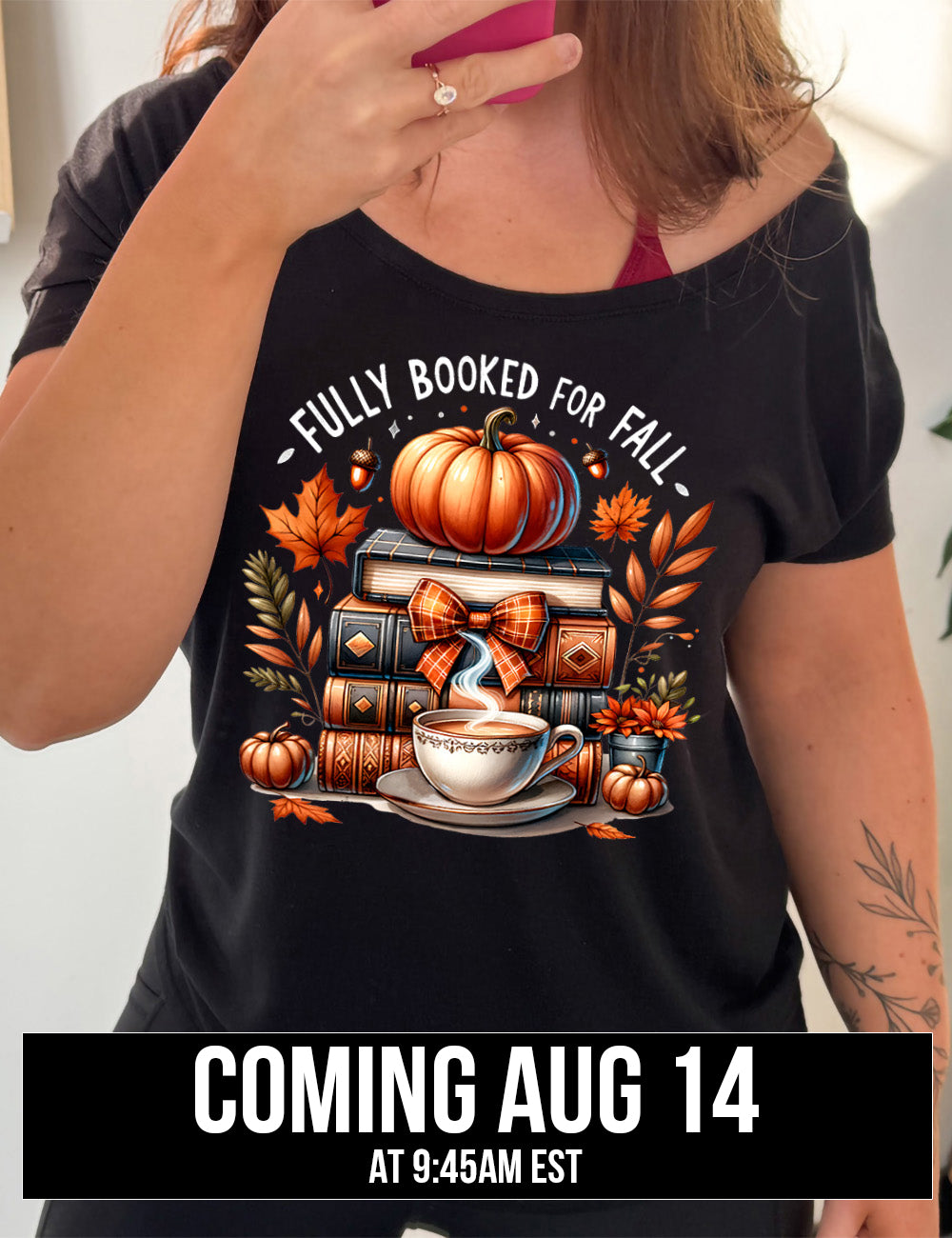 black slouchy tee with the colorful graphic of a stack of books, topped with a pumpkin, surrounded by plants and acorns and two little pumpkins, and a steaming teacup in front, with the words above saying "fully booked for fall" coming august 14th