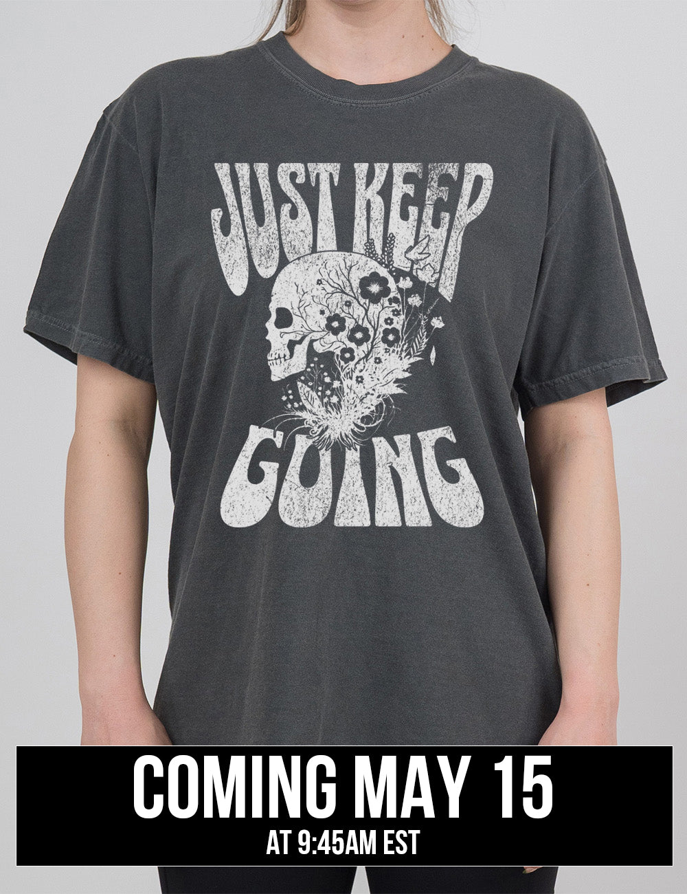 pepper modern tee with print placement on the front, with the words "just keep going" on it, with the graphic of a skull's profile, growing among plants, coming may 15th
