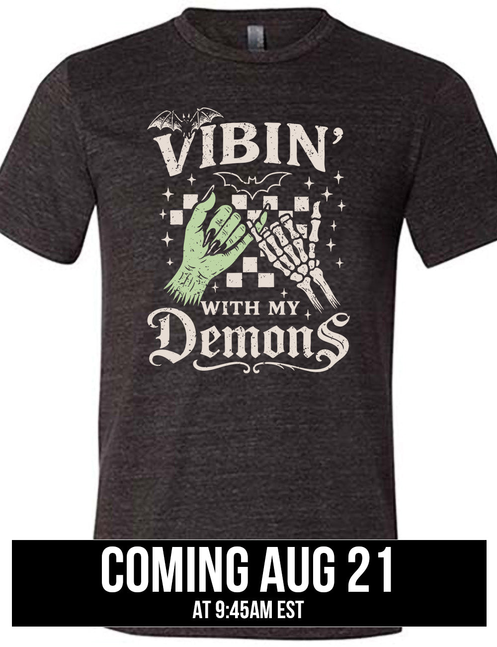 black unisex tee with words saying "Vibin' with my Demons", around the graphic of the hands of a zombie and a skeleton doing a pinky promise, in front of a checkered background, and one line-drawn bat and one detailed bat on top, and scattered stars, coming august 21st