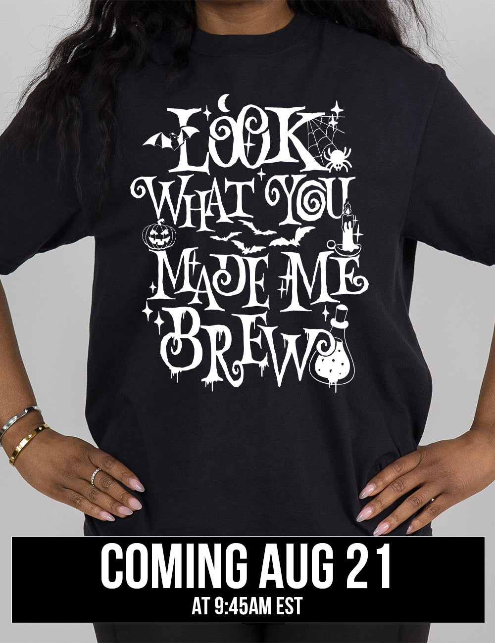 black modern tee with the curly, dripping words saying "look what you made me brew" (with the "o" being a spiral) and the graphics of a potion, a spider in its web, a candle, a bat some bats, stars, and a jack-o-lantern, coming august 21st
