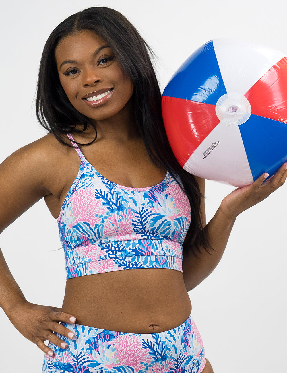 model wearing the blue and pink coral pattern coastline bathing suit top against a white background
