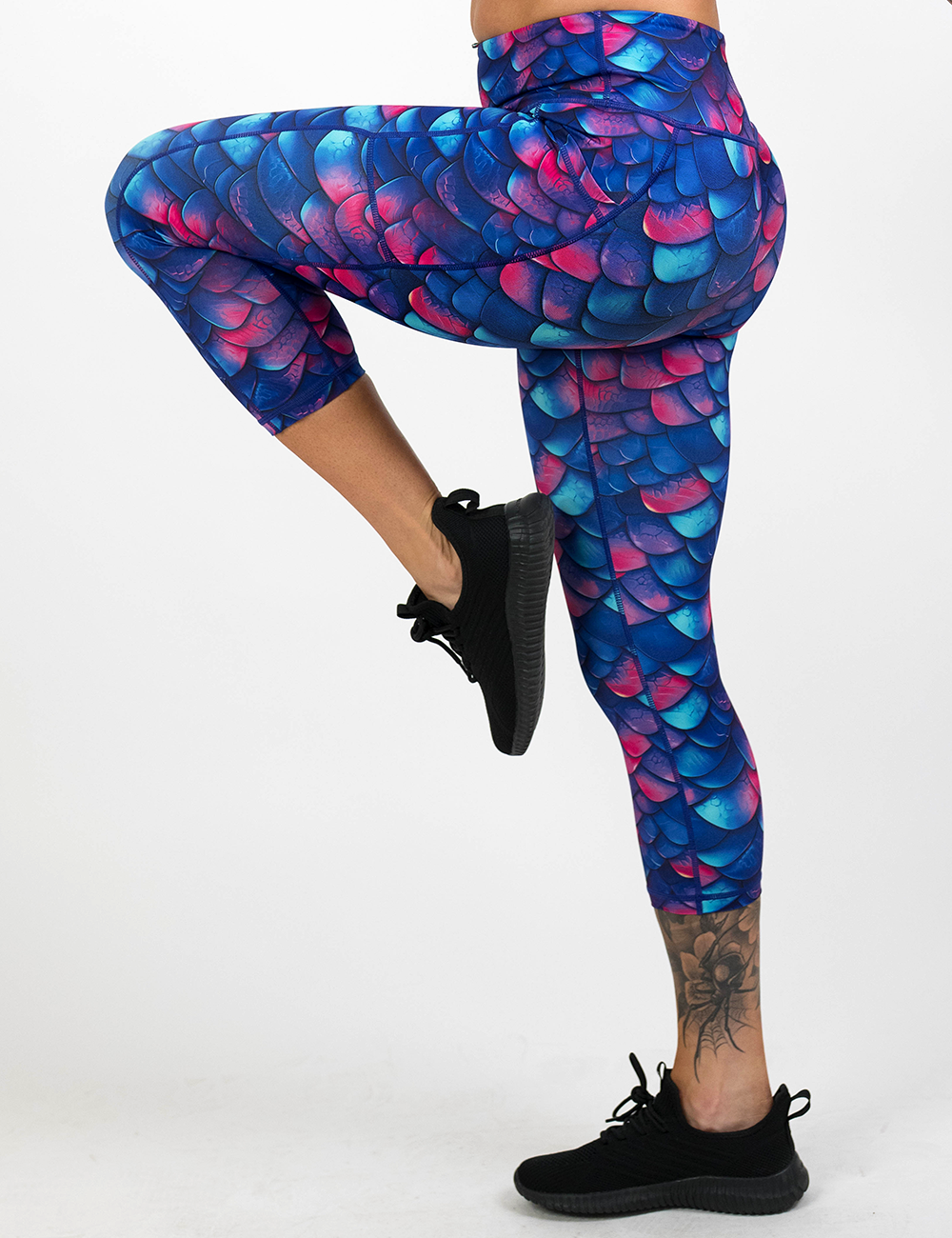 model wearing the blue, purple, and red colored dragon scale capri leggings against a white background