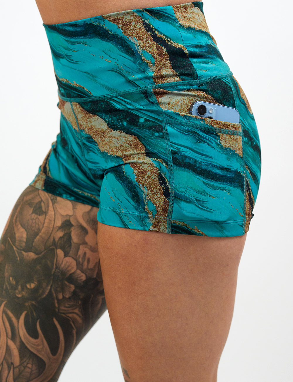 close up of the 2.5 inch  blue ocean with gold streaks patterned shorts with a phone in its pocket