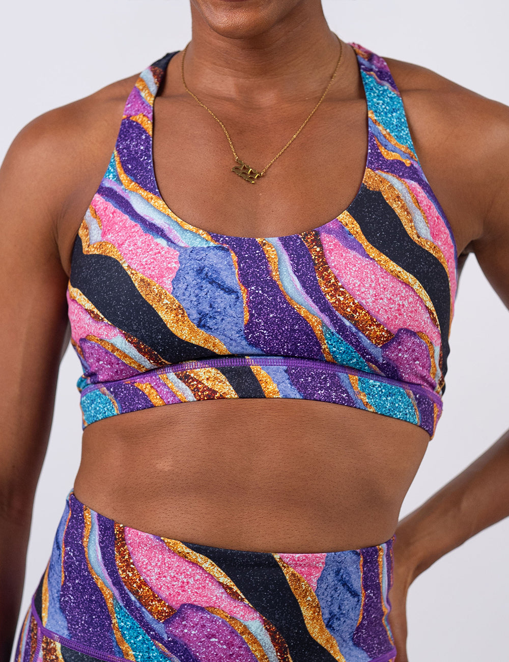 front of the purple, gold, black, blue, and pink abstract stripes sports bra