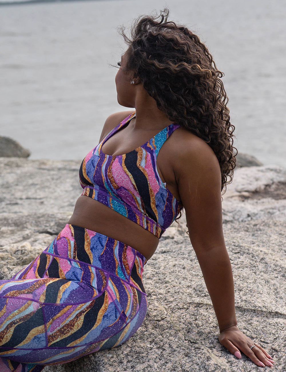 model wearing the purple, gold, black, blue, and pink abstract stripes sports bra and leggings