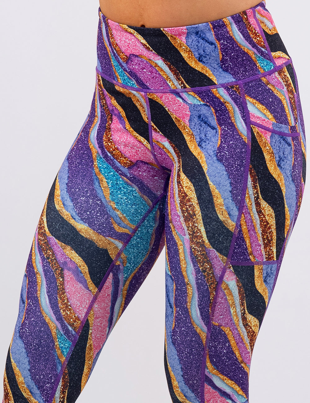 front of the purple, gold, black, blue, and pink abstract stripes leggings against a white background