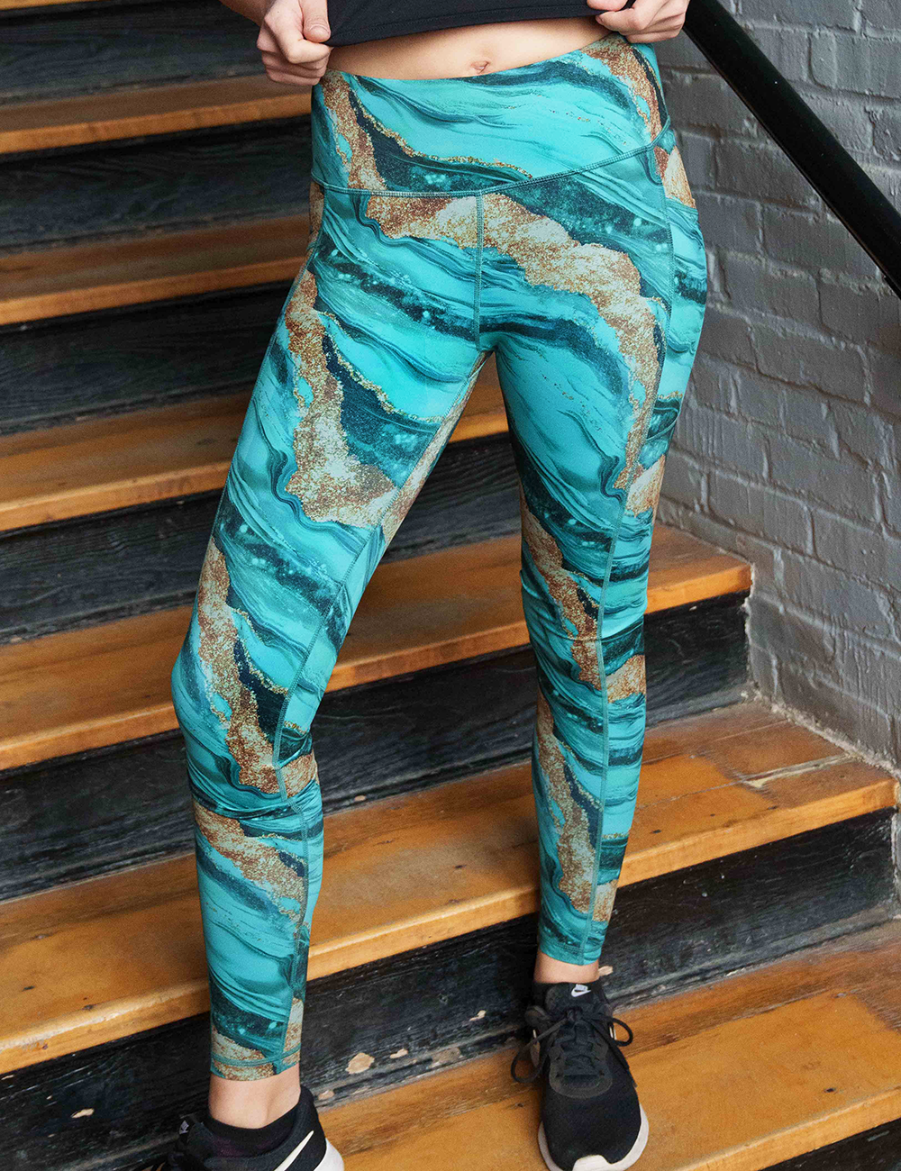 blue ocean with gold streaks patterned full length leggings facing the front  on stairs