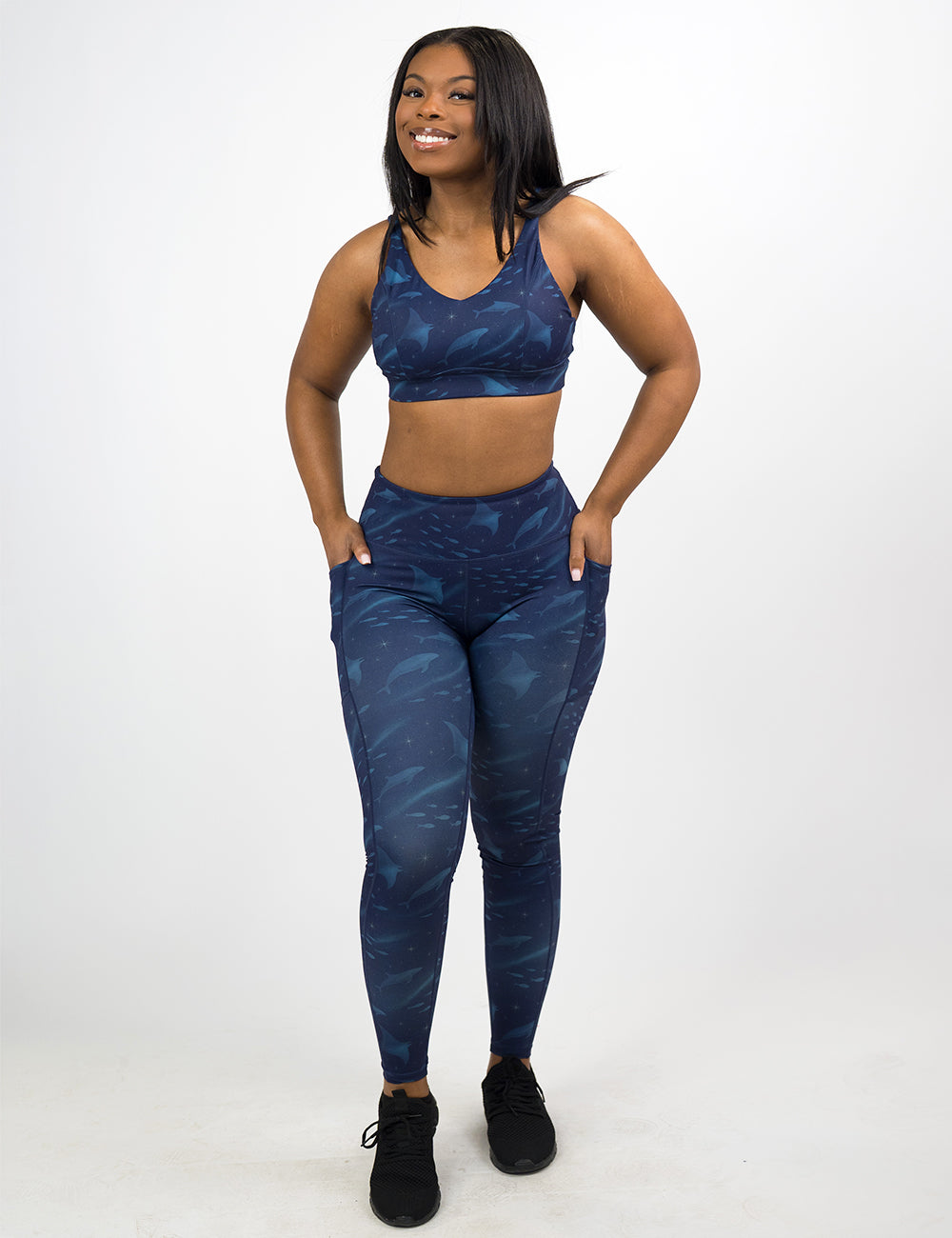 model wearing the full length dark blue ocean filled with sting rays, whales, and fish leggings against a white background