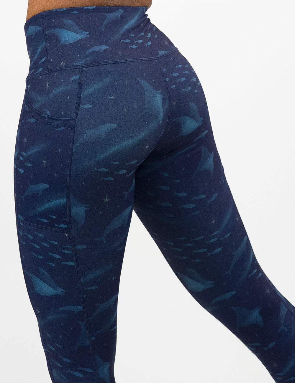 front of the dark blue ocean filled with sting rays, whales, and fish leggings against a white background