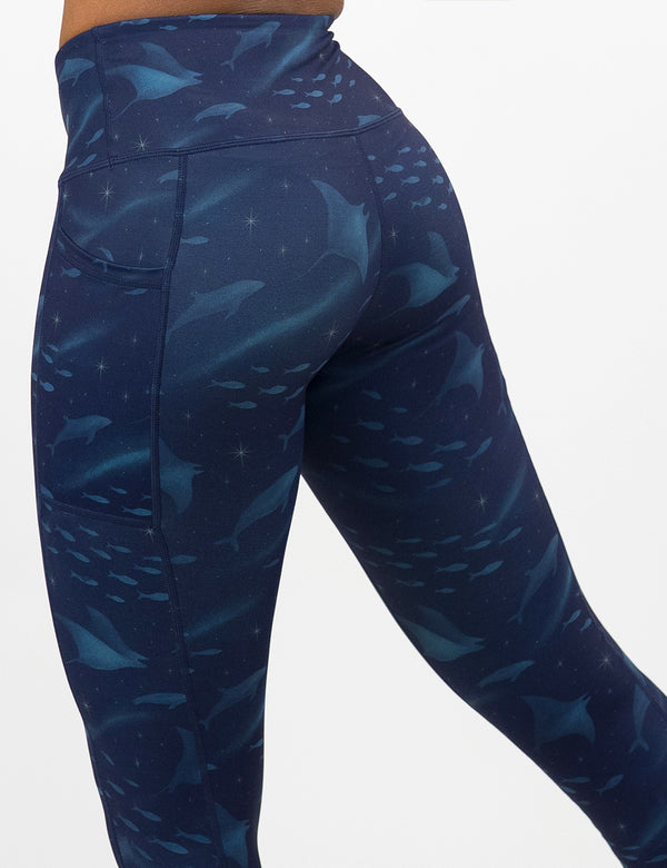 front of the dark blue ocean filled with sting rays, whales, and fish leggings against a white background