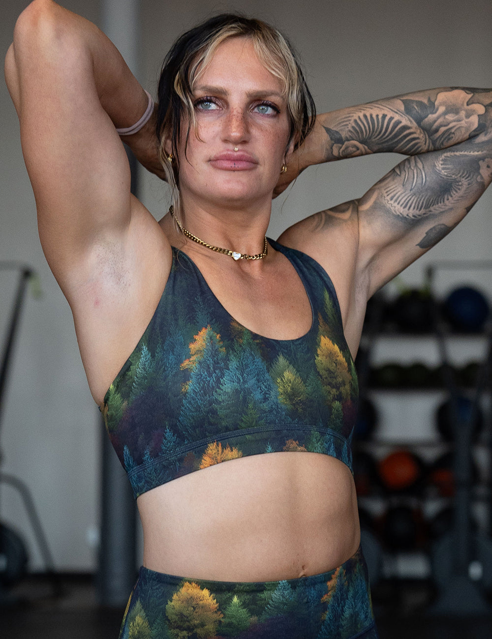 model wearing the orange, green, and bluish green trees bra in the gym