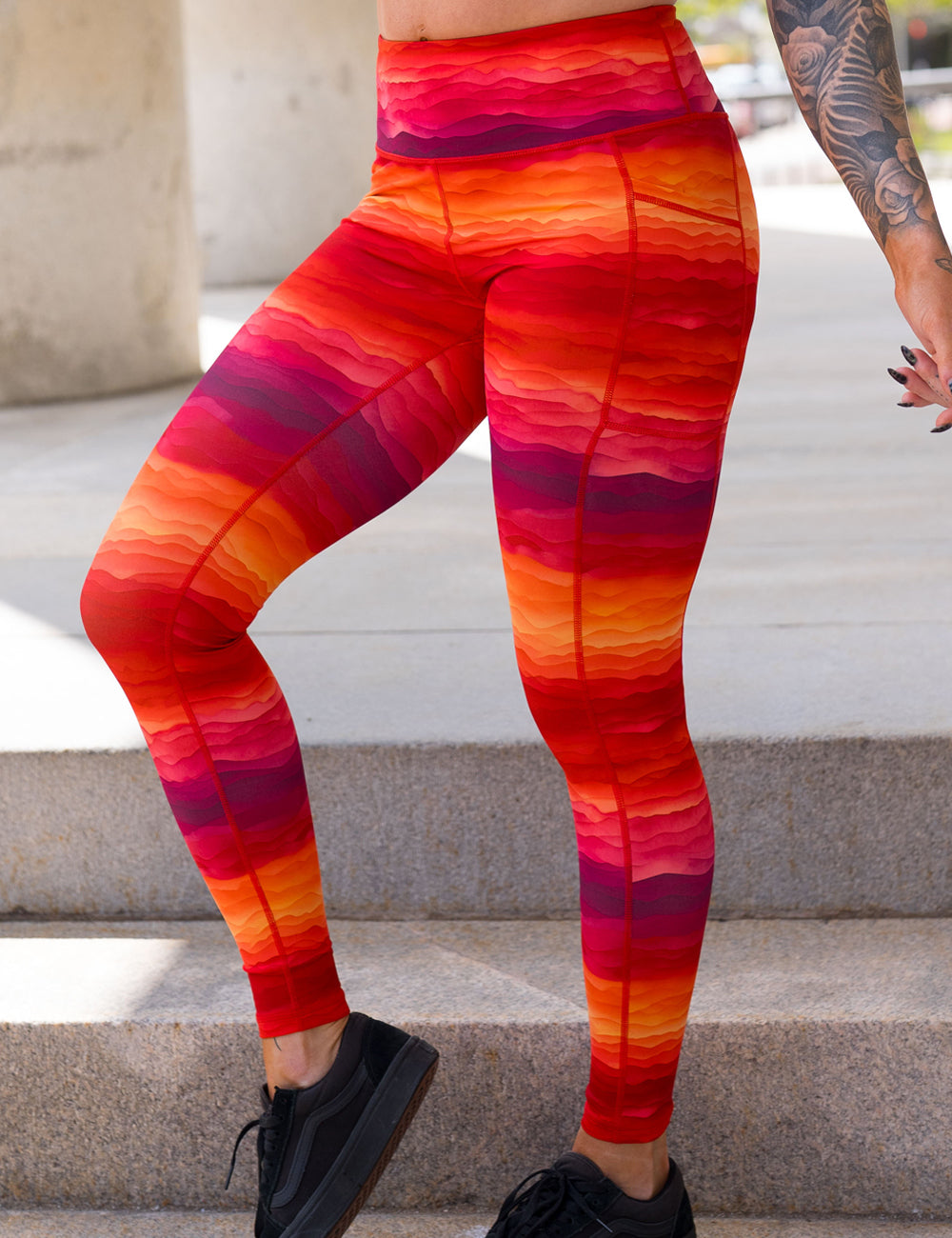 front of the orange, red, and yellow sunset stripes pattern full length leggings