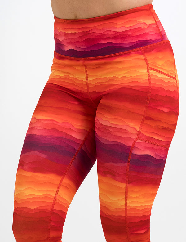 front of the orange, red, and yellow sunset stripes pattern leggings against a white background