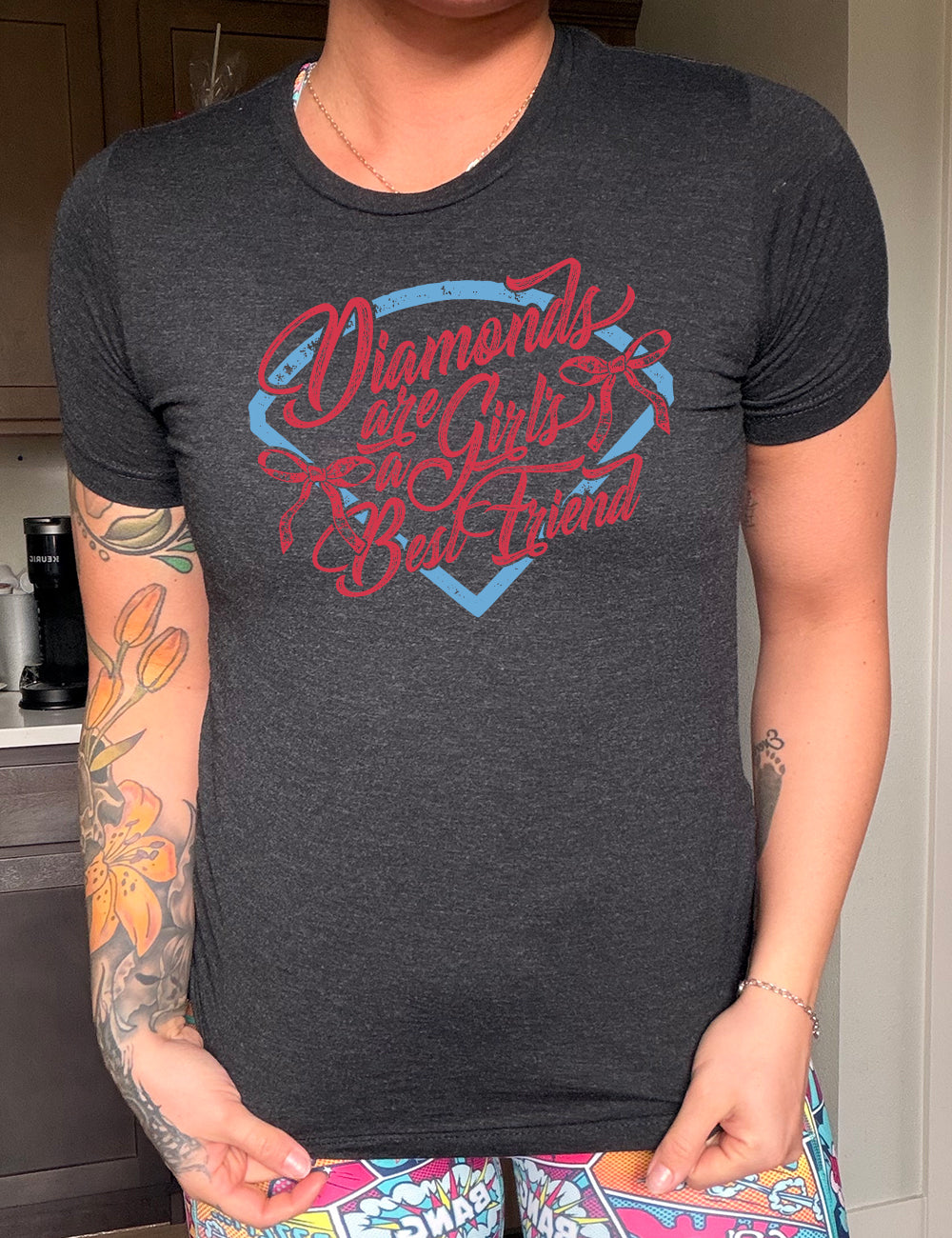 black unisex tee with the words "diamonds are a girl's best friend" on it, with two bows, all in front of a baseball diamond