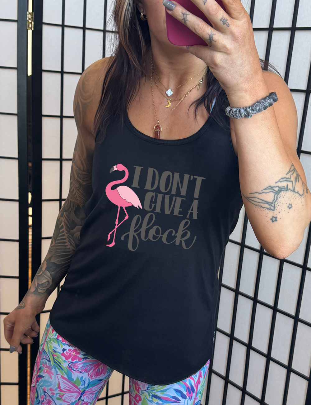 black flowy racerback tank with the words "I don't give a flock" on it, with the graphic of a flamingo next to these words, leg raised