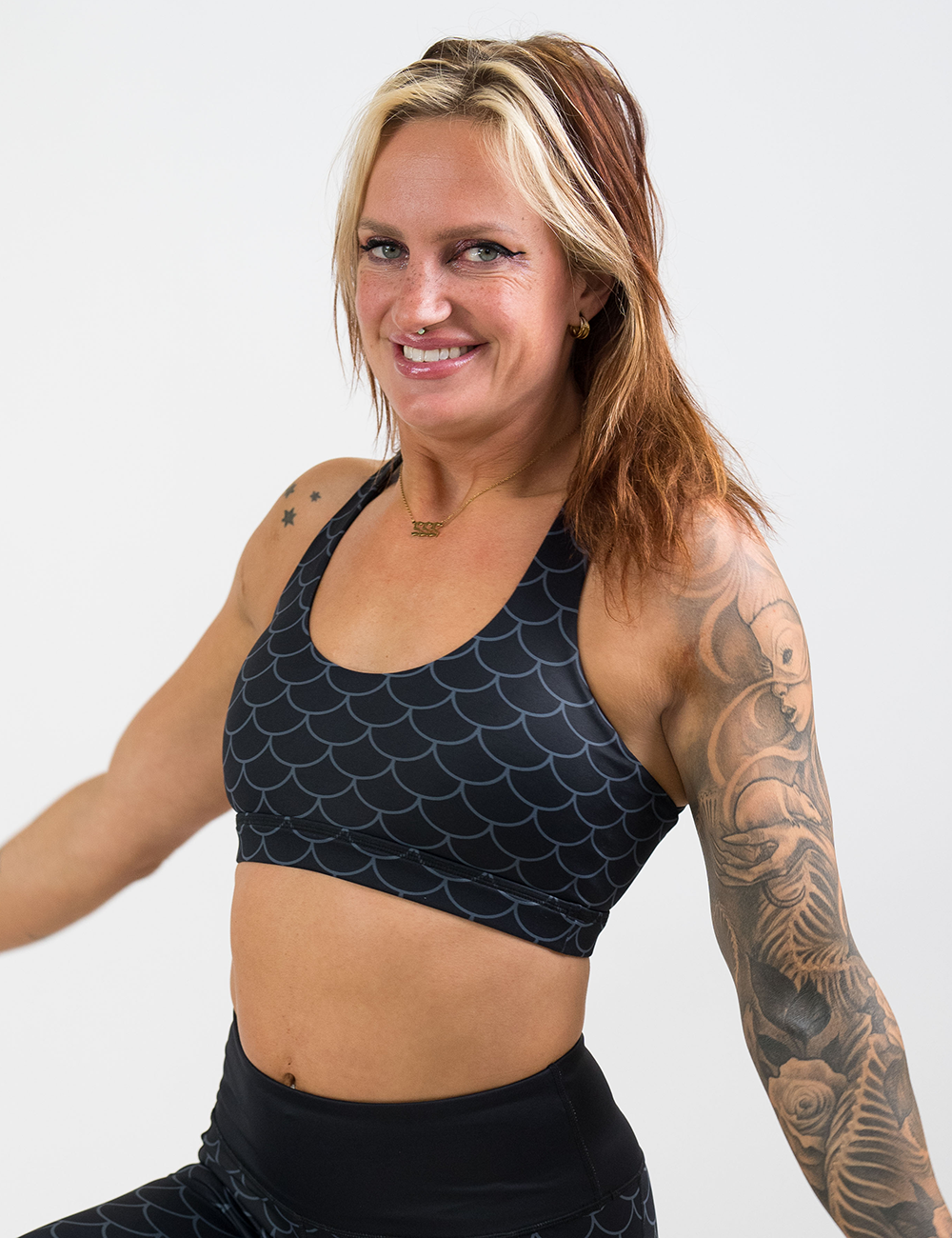 model wearing the dragon scale outline against a dark background pattern butterfly back bra against a white background