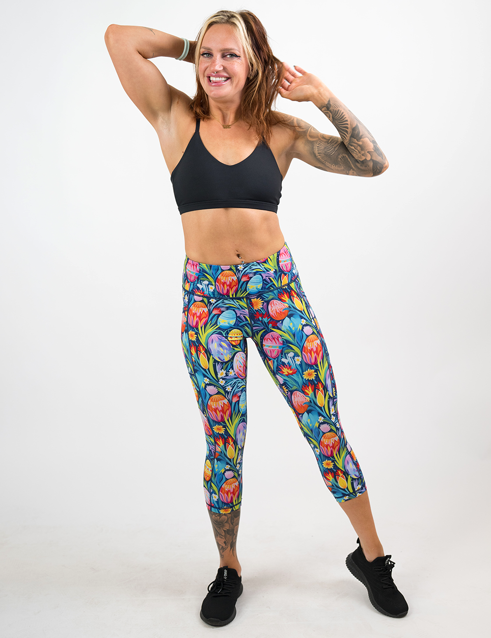 model wearing the easter eggs in a field of flowers pattern capri leggings against a white background