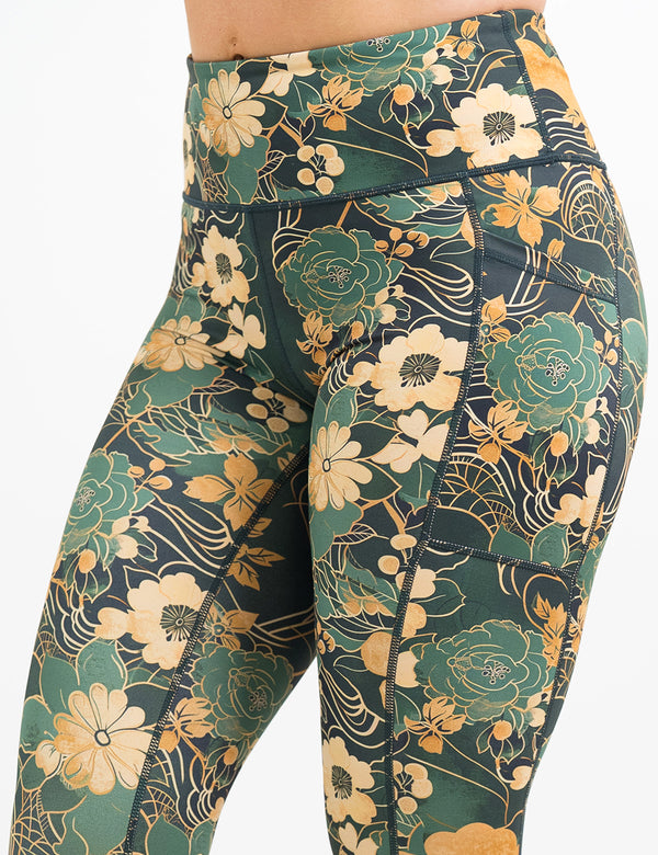 close up of the gold and green flowers with gold accents pattern leggings against a white background