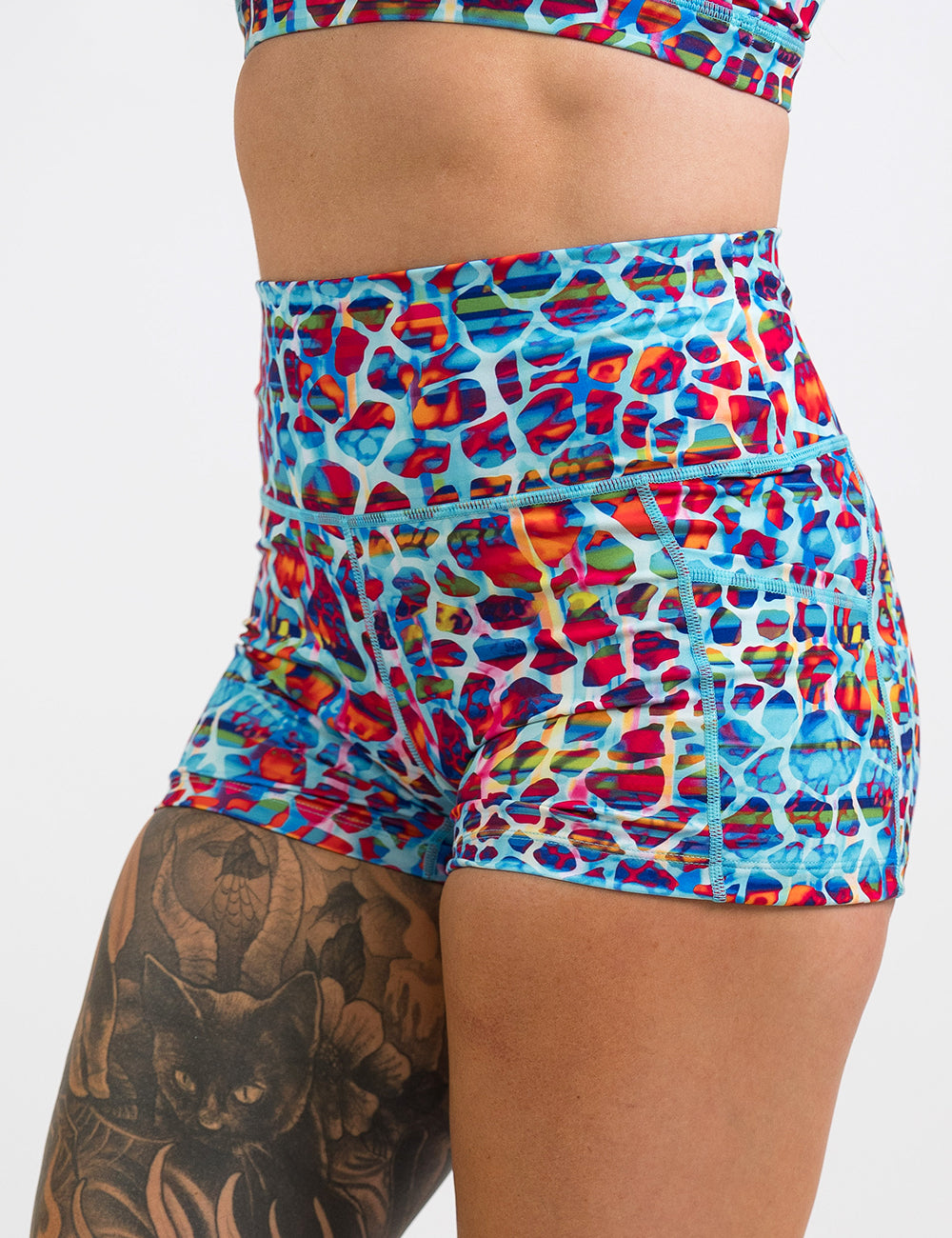 front of the 2.5 inch blue, red, teal, and yellow mosaic style shorts against a white background