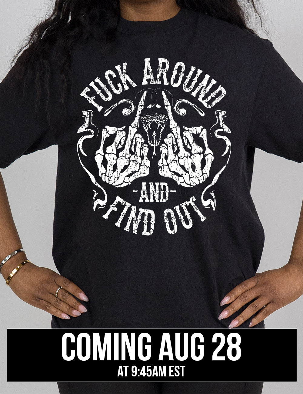 black modern tee with the graphic of two skeletal hands both giving the middle finger, around a snake's head with its tongue out, with the words circling around this all saying "fuck around and find out" with smokey lines completing the sides of the circle, coming august 28th