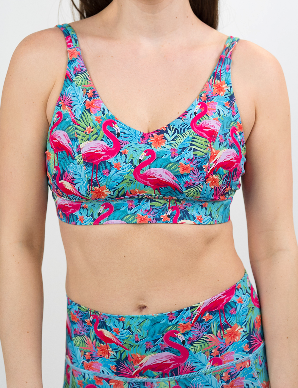front of the flamingos against a colorful floral background patterned vitality bra against a white background