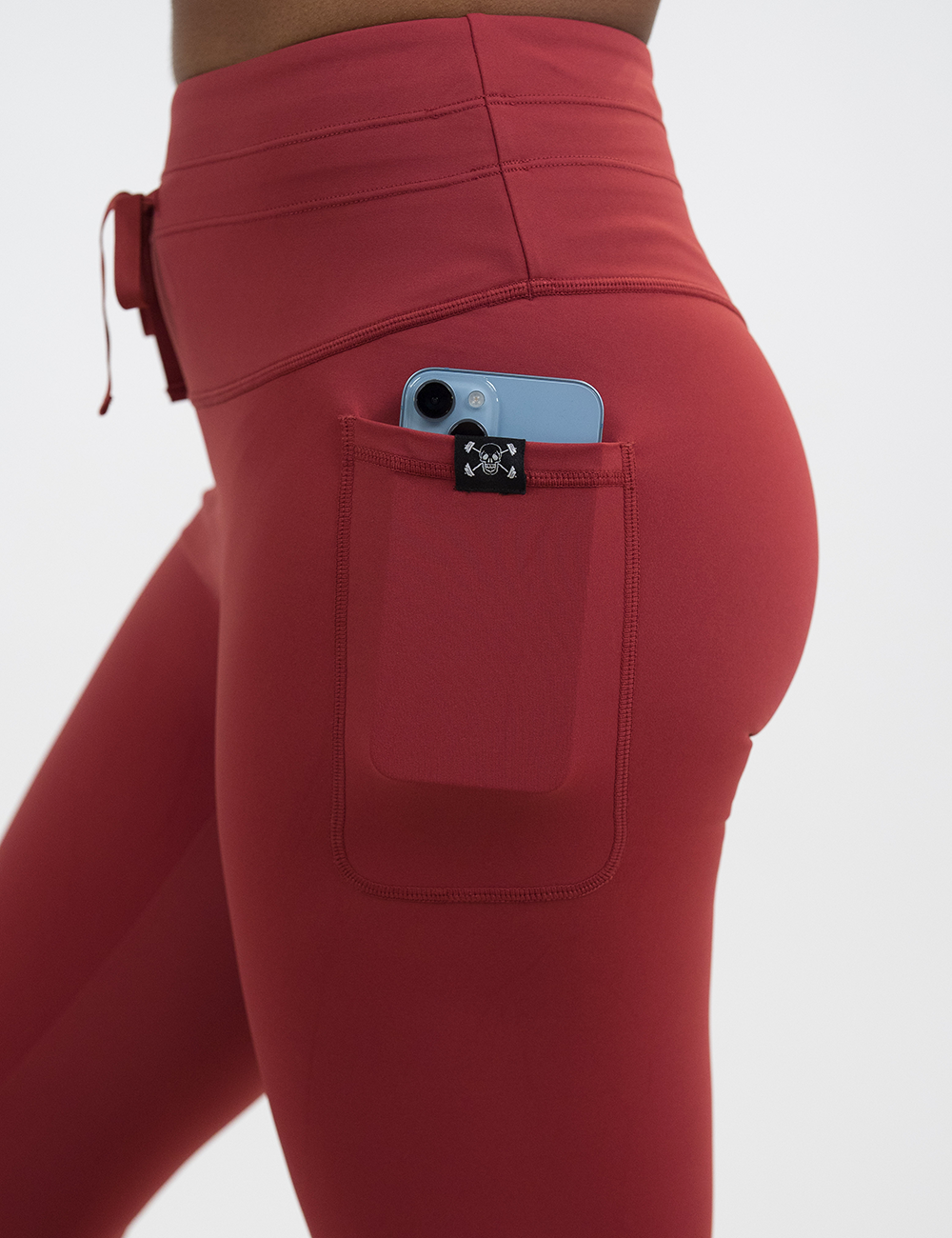close up of the red drawstring leggings showing a phone in the pocket