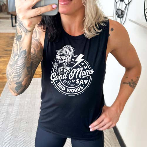 model wearing a black muscle tank with the saying "good moms say bad words" and a female skeleton rock symbol hand and lightning bolt