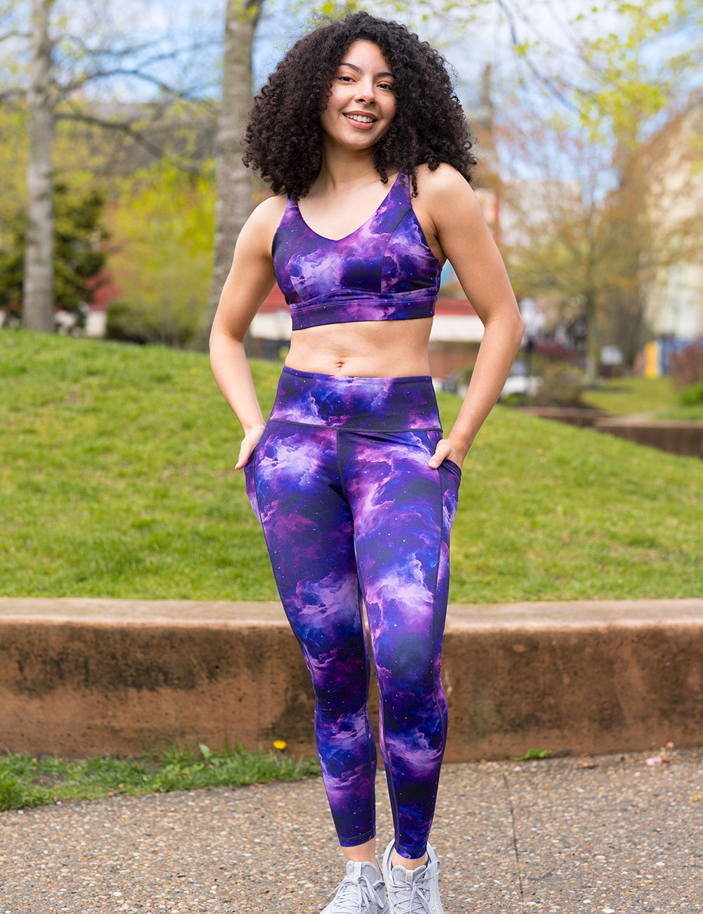 model wearing the purple space patterned leggings and bra in the park