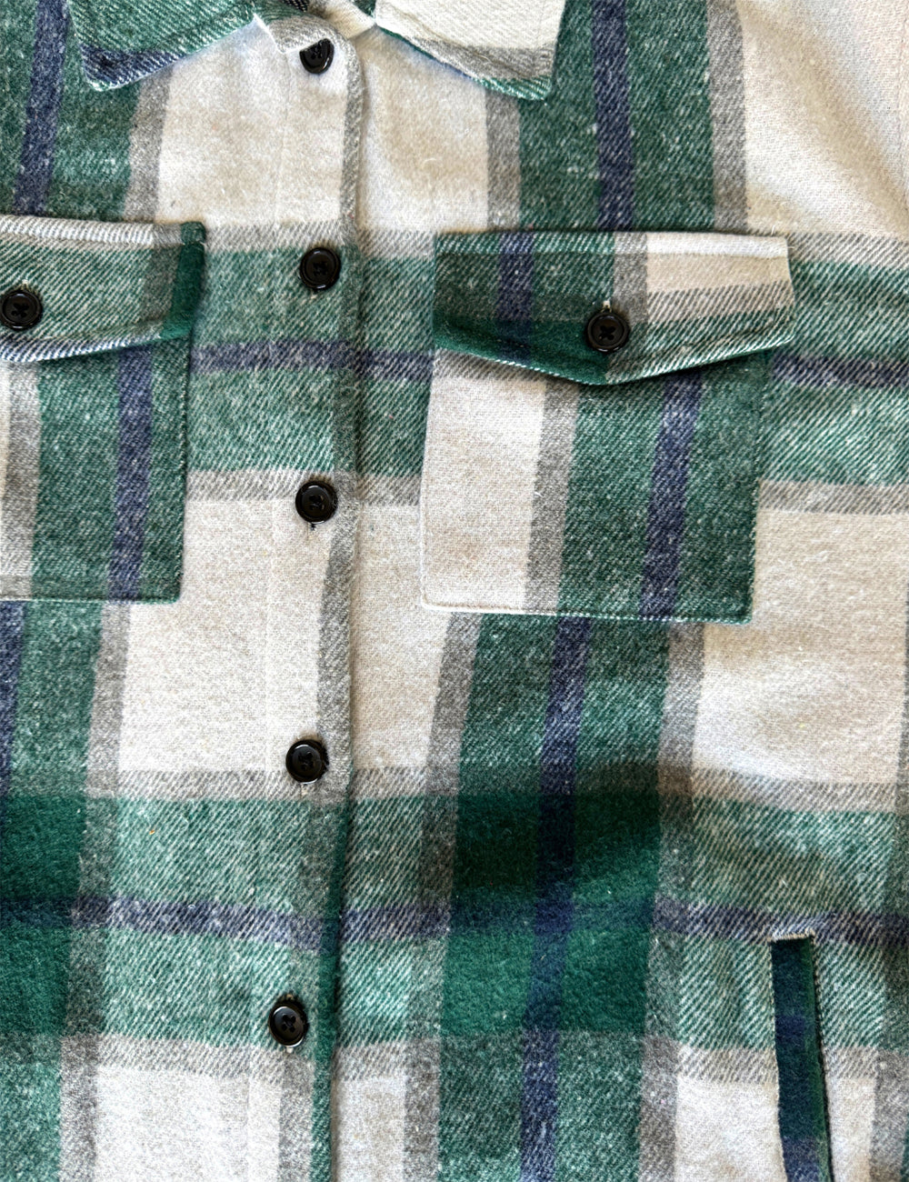 close up of the green, dark blue, grey, and white plaid jacket