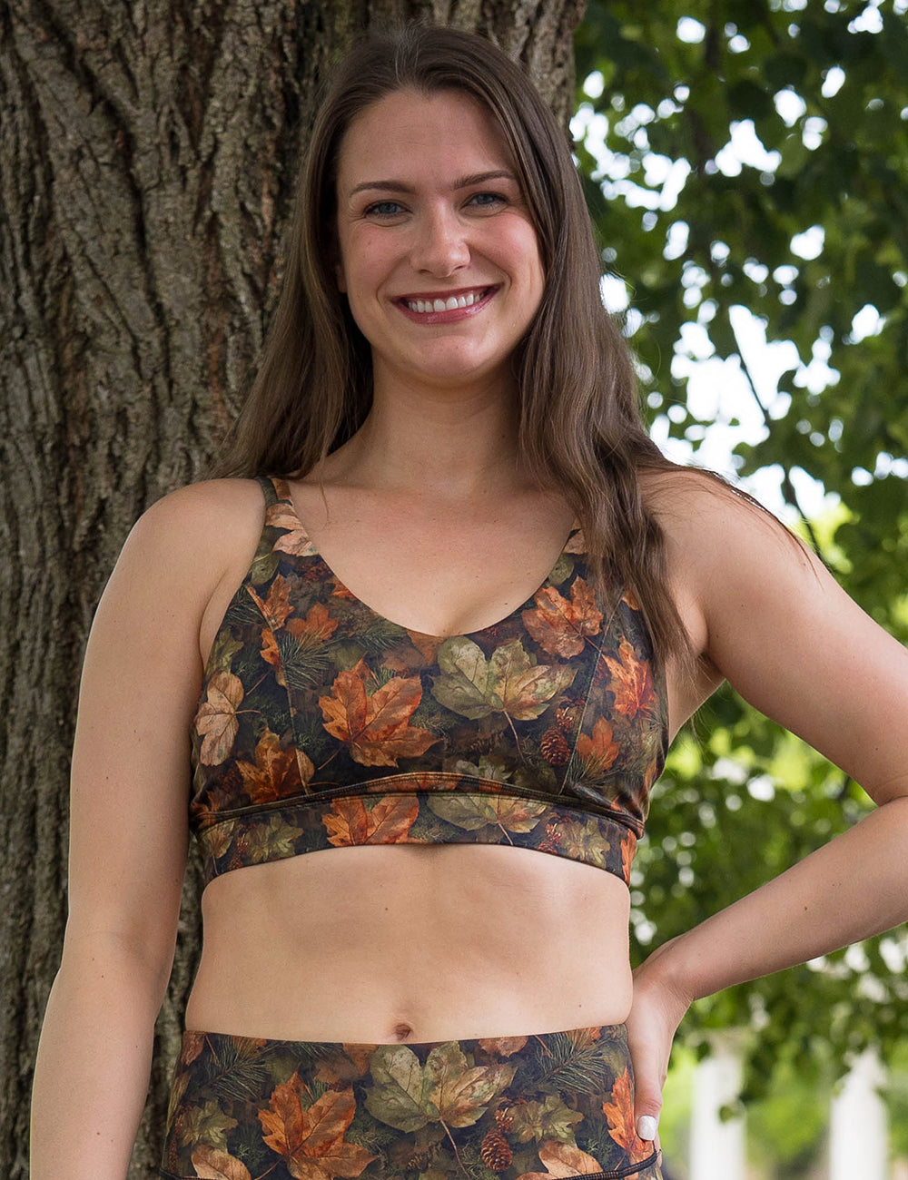 model wearing the forest floor covered in leaves bra in front of a tree