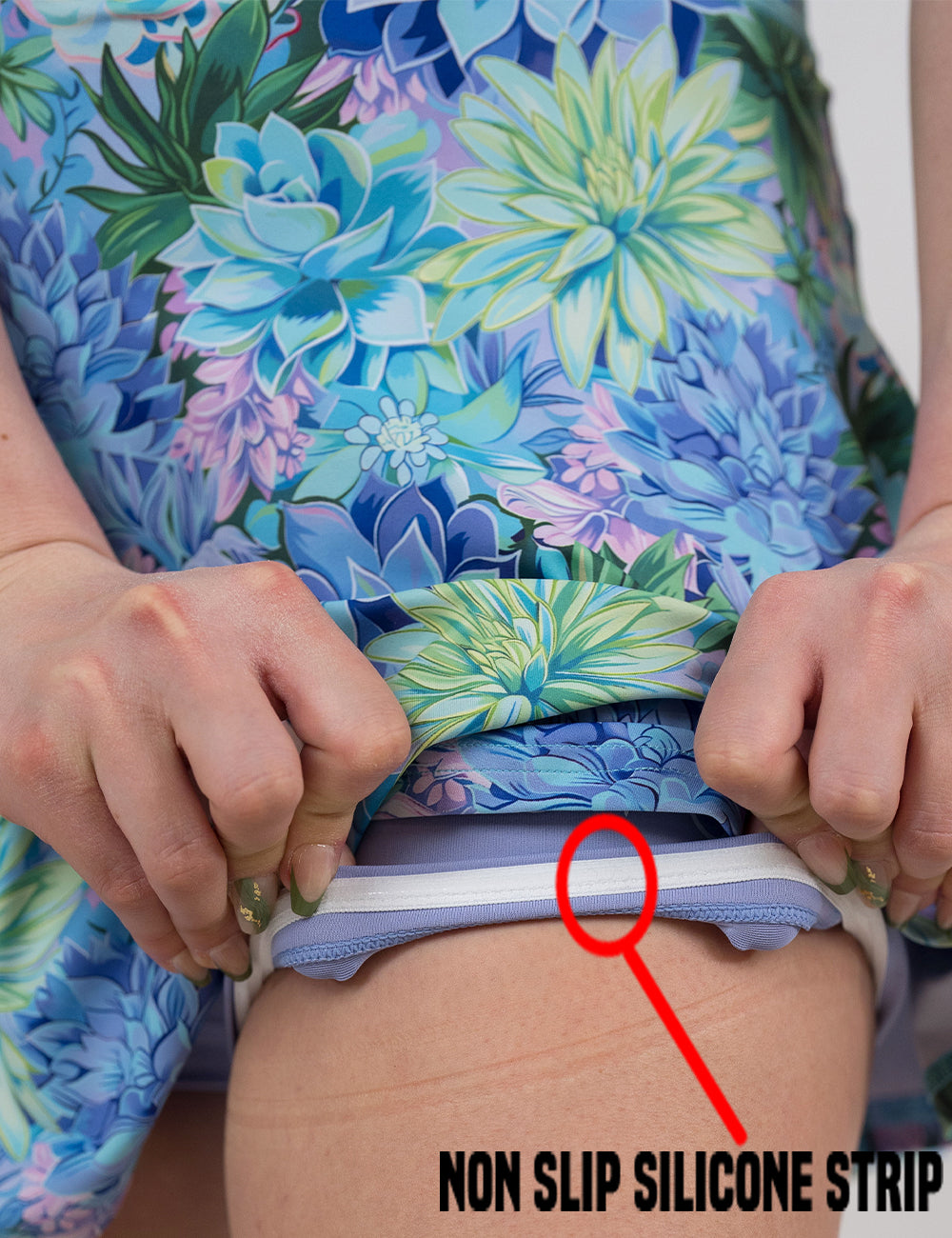close up of the blue and green flower print skirt being rolled up to show the non slip silicone strip found in the lining of the under shorts