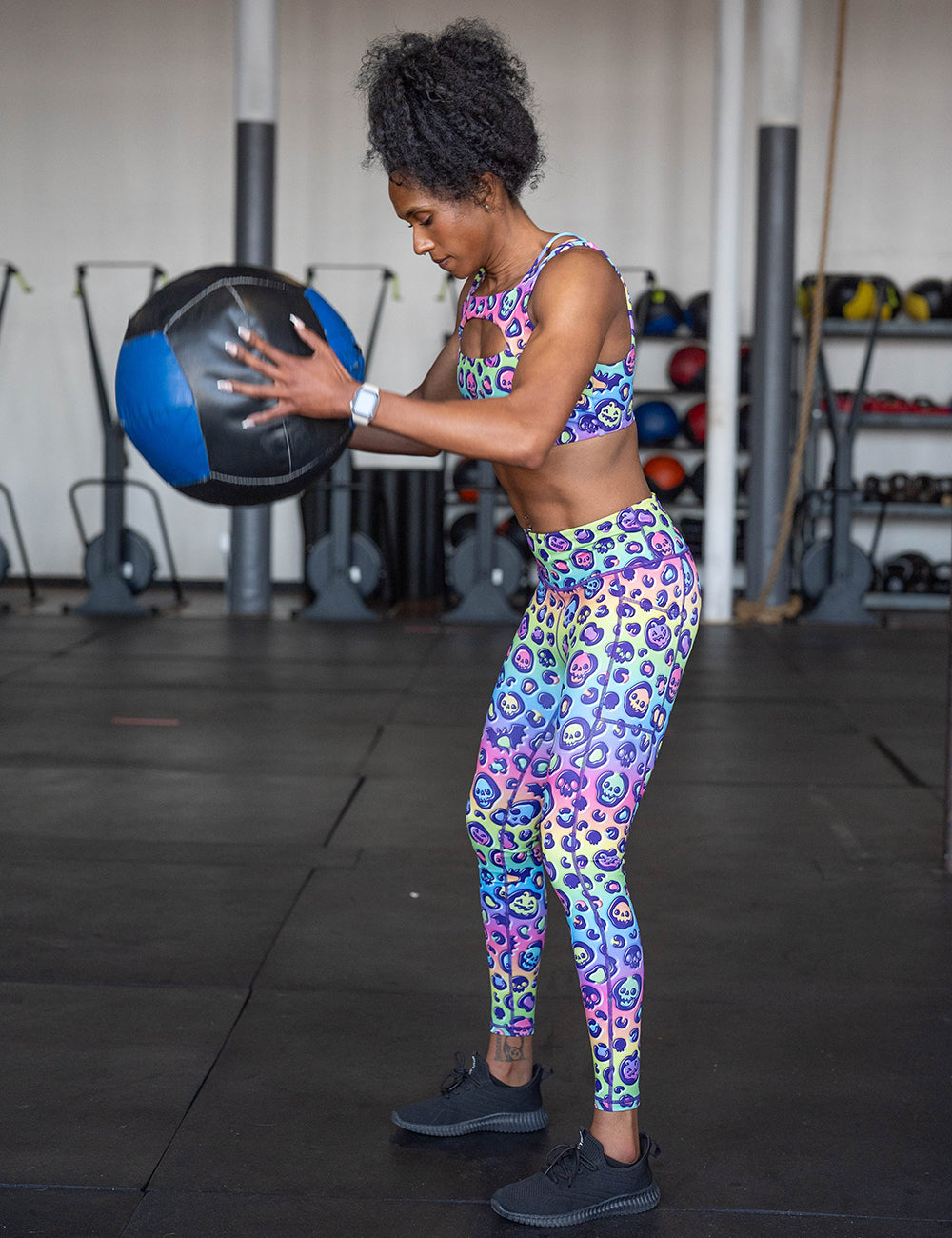 model wearing the rainbow leopard print pumpkins and skulls full length leggings working out with a medicine ball