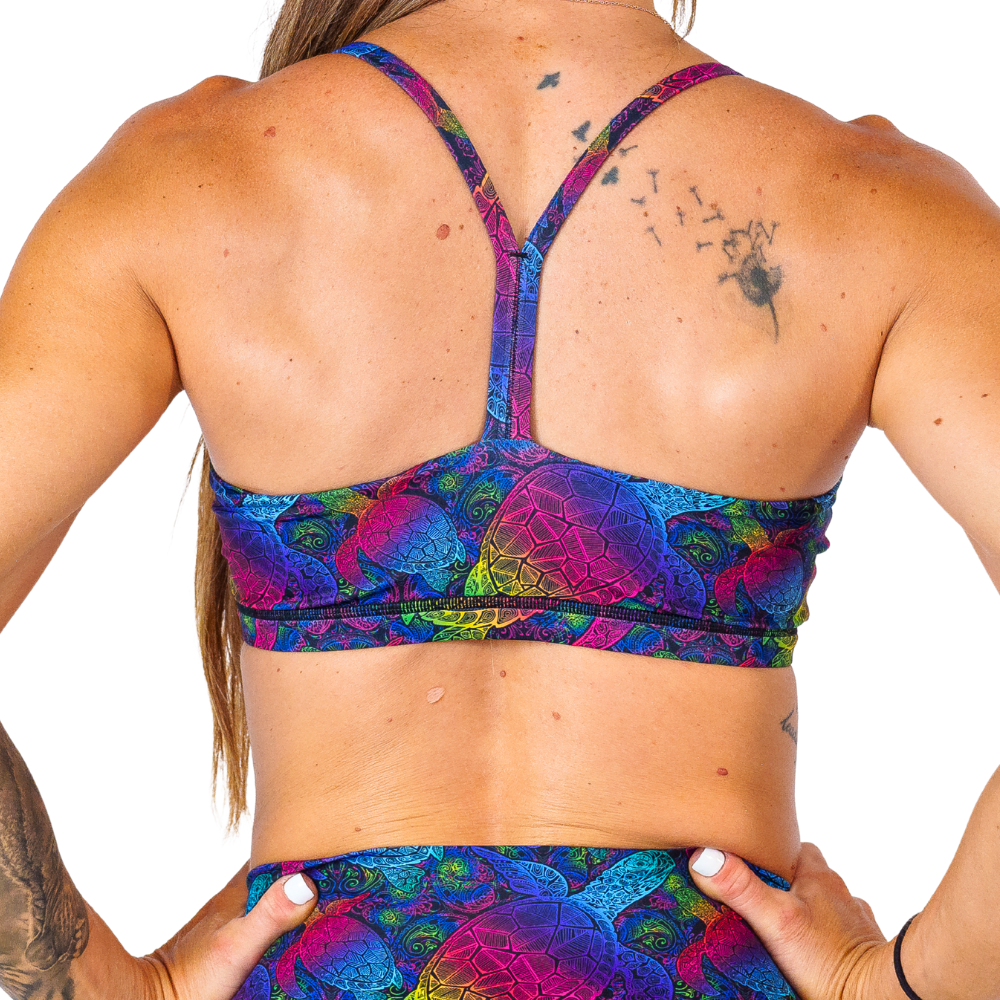 back of the move free rainbow pink, yellow, blue, green and purple ombre turtle print move free bra against a white background 