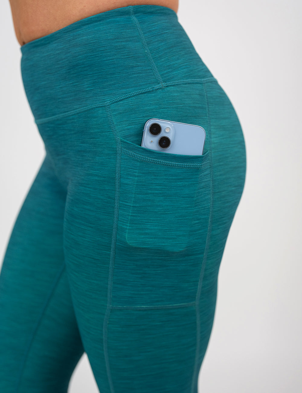 close up of the teal heather pattern leggings with a phone in its pocket