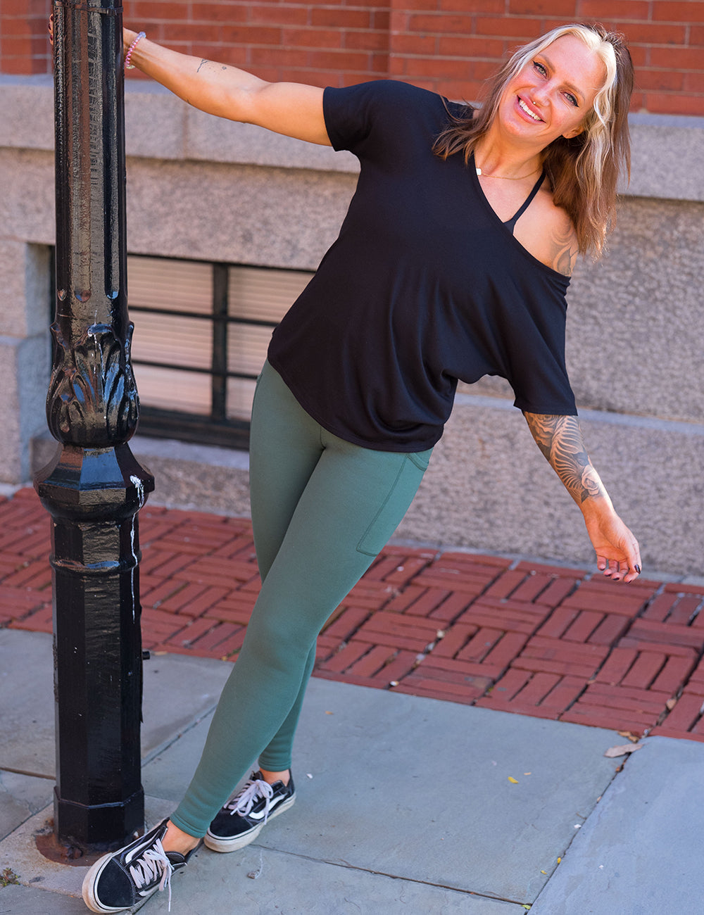model wearing the dark green fleece lined leggings and a off the shoulder black tee