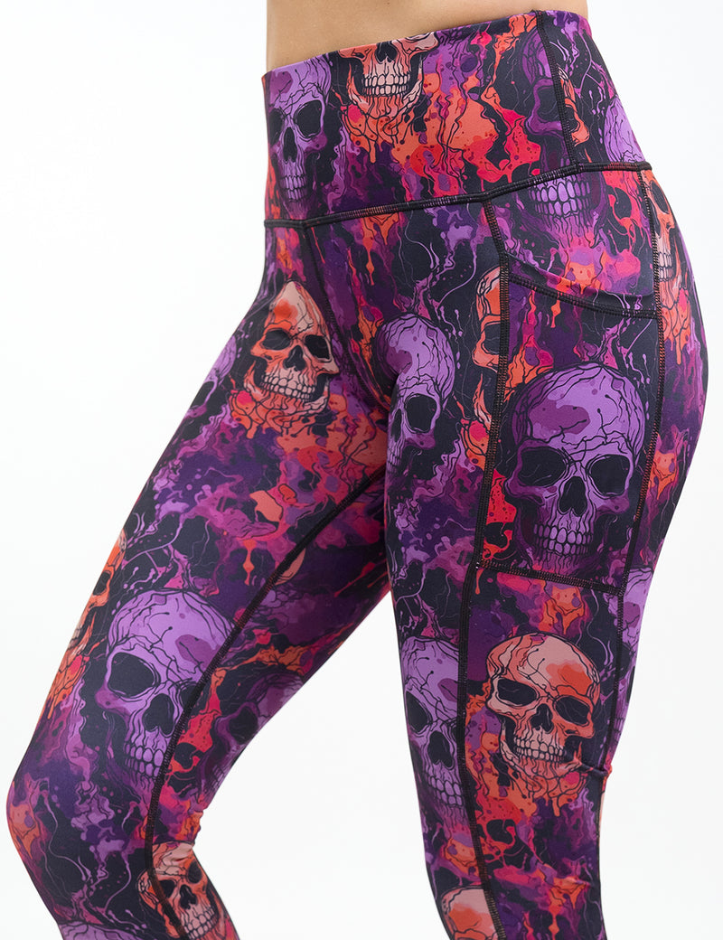 front of the purple and orange skull patterned leggings against a white background