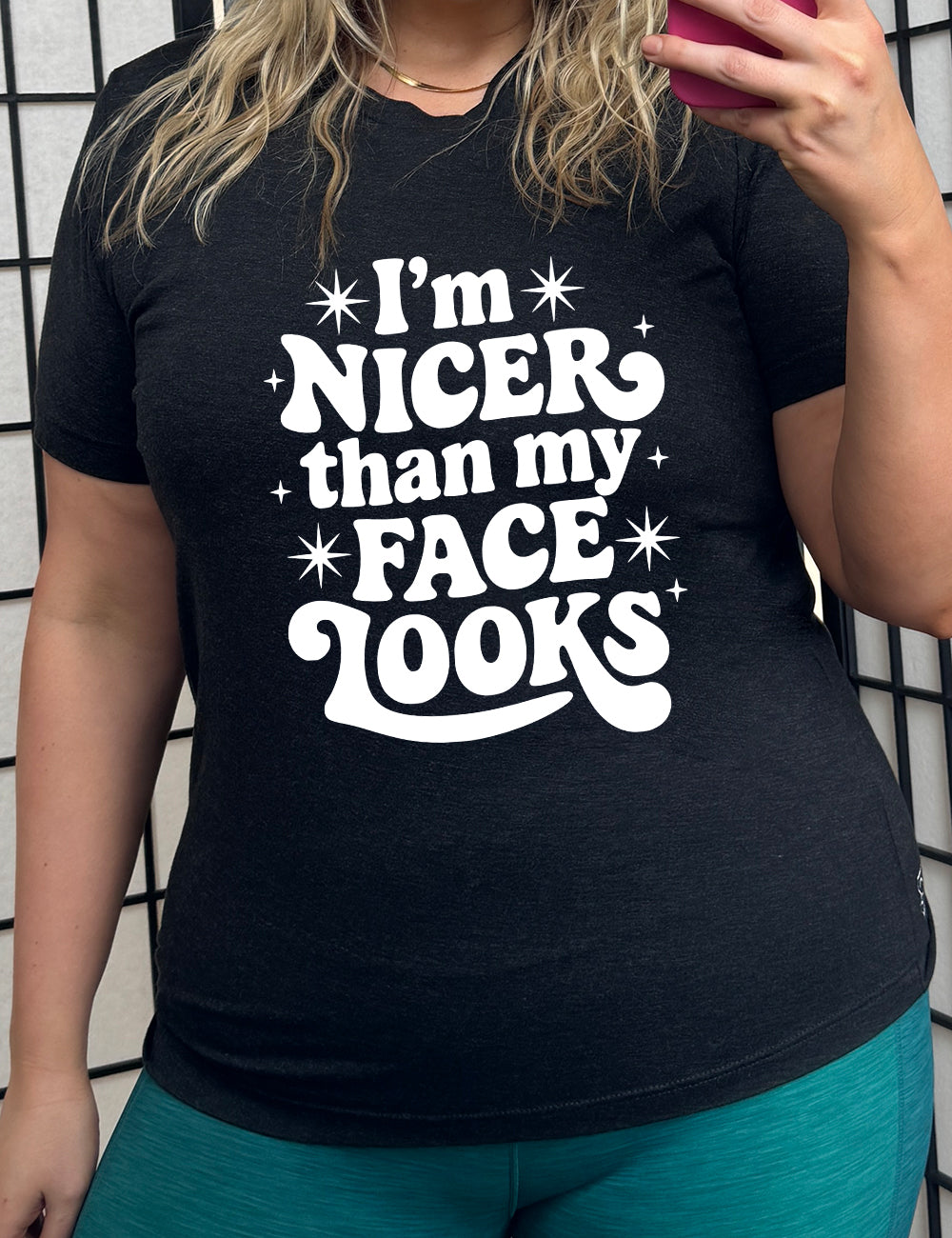 black unisex tee with the words "I'm nicer than my face looks" surrounded by stars